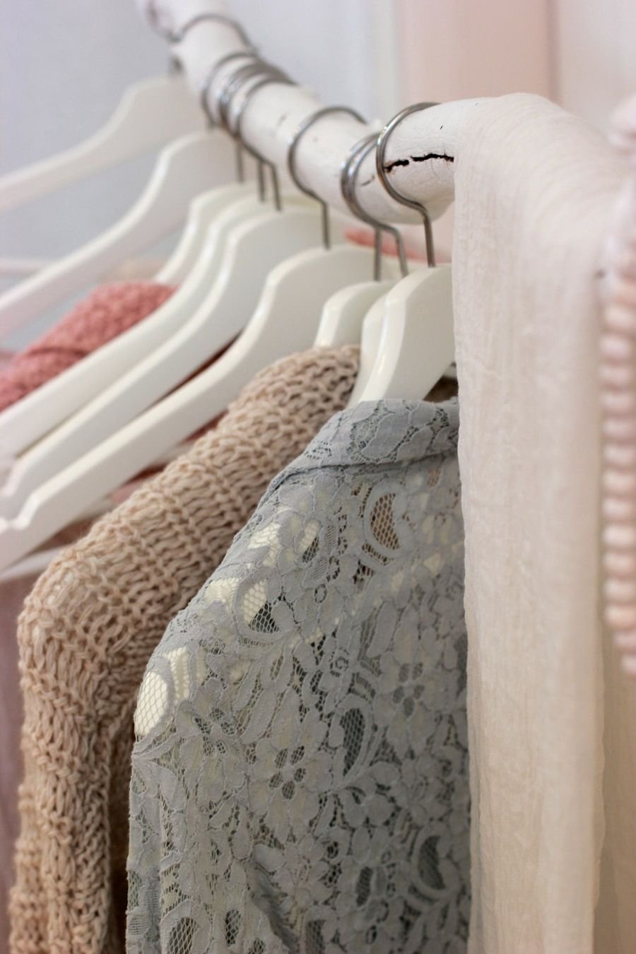 Pale garments on matching hangers seen in close crop, blush and ivory